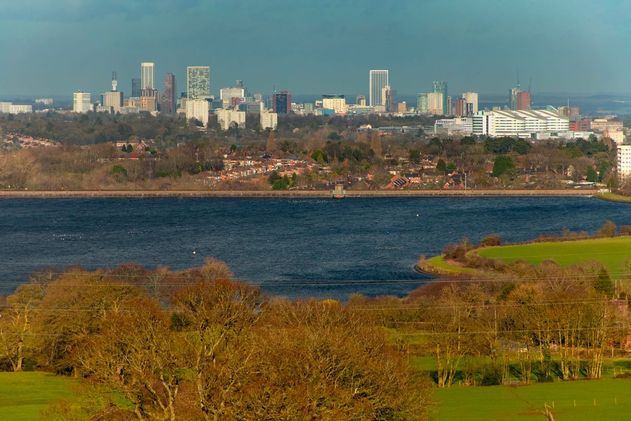The Birmingham skyline across open water on a bright day