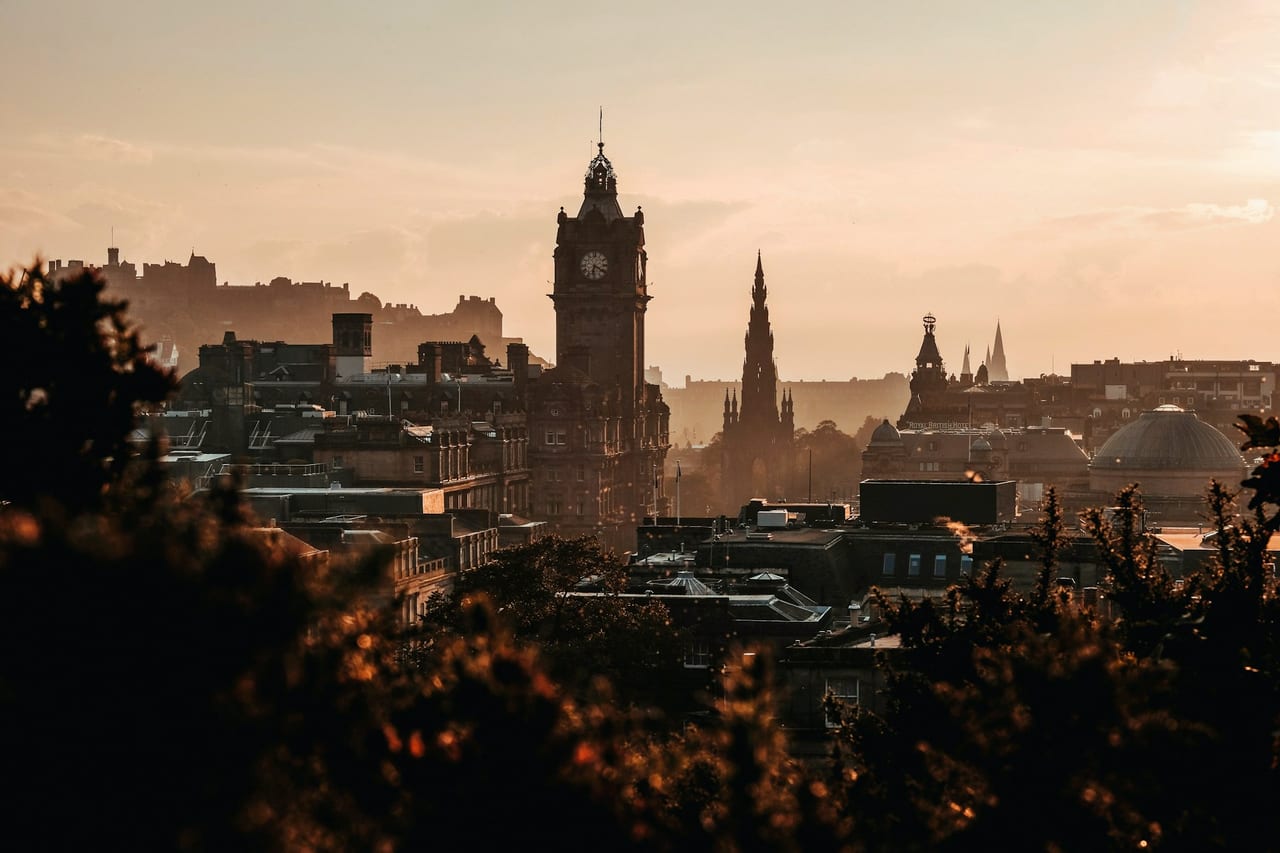Edinburgh's Old Town skyline in golden haze — clock tower and monument spires